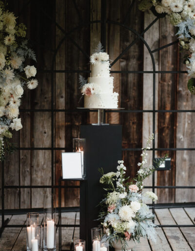 Hochzeitstorte vor dem Traubogen mit Blumenschmuck und Kerzendeko, Hochzeitsplanerin Ronja Baumbach, Österreich und Allgäu