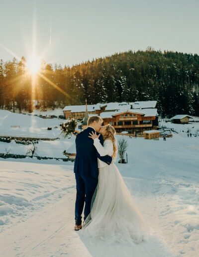 Brautpaar bei ihrer Winterhochzeit in den Bergen im Sonnenuntergang