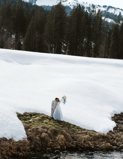 Brautpaar bei ihrem Brautpaarshooting ihrer Berghochzeit im Winter mit exklusivem Brautstrauß mit atemberaubendem Panorama