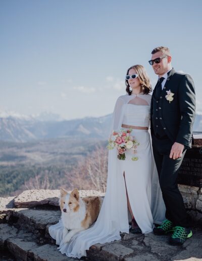 Brautpaar mit ihrem Hund am Gipfelkreuz beim Fotoshooting auf ihrer Berghochzeit in Österreich
