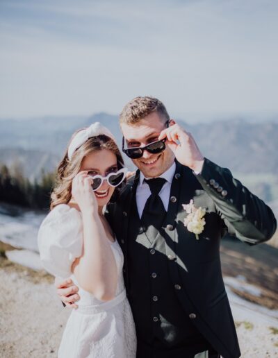 Brautpaar mit coolen Brillen beim Empfang auf ihrer Berghochzeit