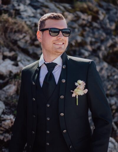 Bräutigam mit Anstecker und Hochzeitsanzug auf seiner Berghochzeit