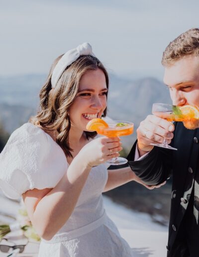 Glückliches Brautpaar trinkt Aperol bei ihrer Hochzeit in den Bergen