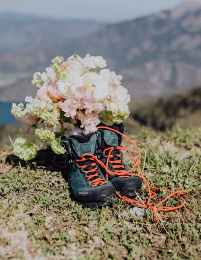 Detailfoto Berghochzeit Brautstrauß und Wanderschuhe mit Bergen im Hintergrund