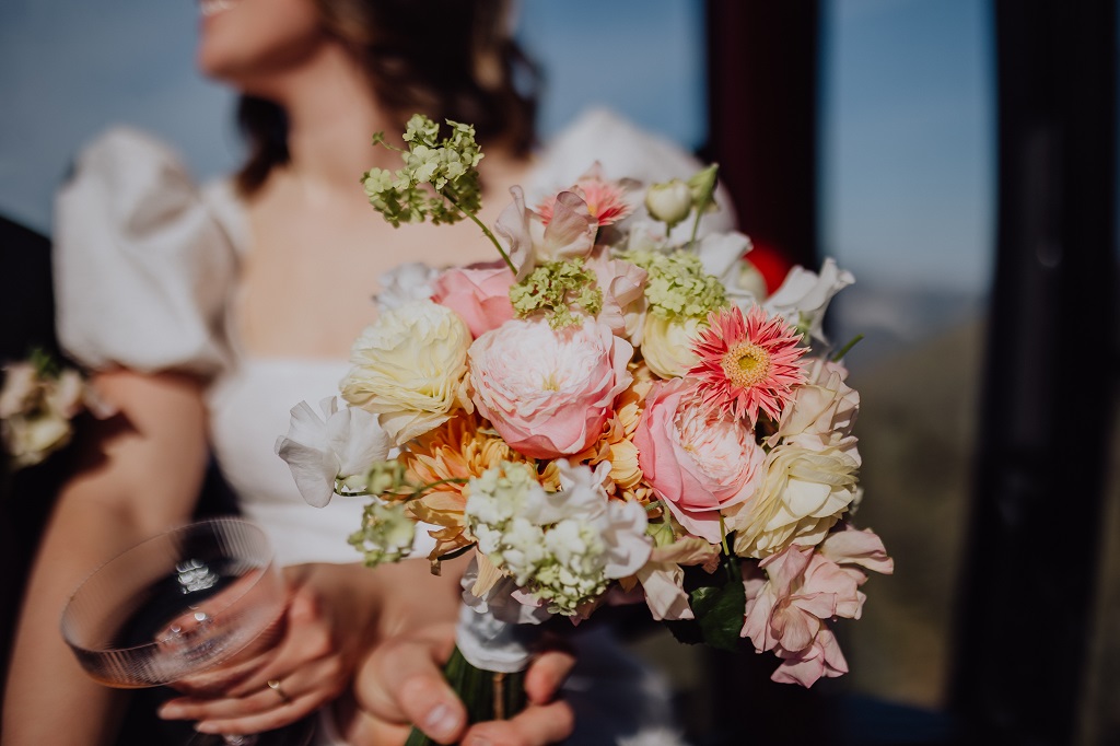 Ronja Weddings Hochzeitsplanung Hochzeit in den Bergen Zeremonienmeister Innsbruck Mittenwald Alpen Frühlingshafter Brautstrauß im Detail bei der Gondelfahrt auf den Berg