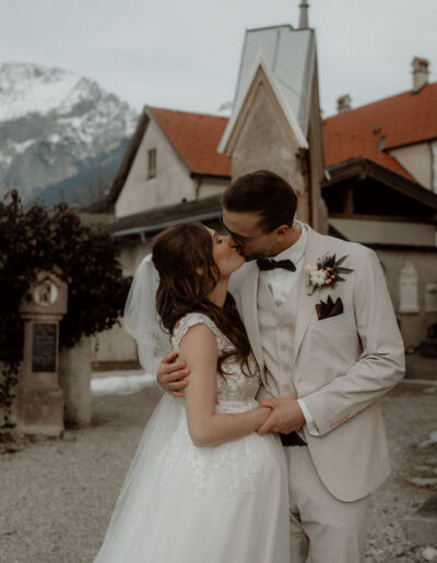 Bride and groom kissing in front of the church at their winter wedding with Wedding Planner