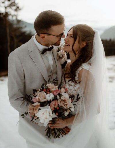 Brautpaar mit Brautstrauß im Schnee auf ihrer Hochzeit am Berg