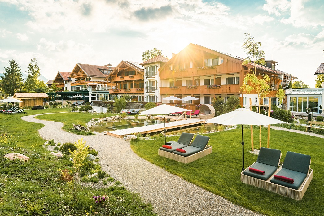 Sommerlicher Hotelgarten mit Naturpool im Hotel Das Rübezahl – Flitterwochen in den Alpen mit Alpenpanorama und Wellness