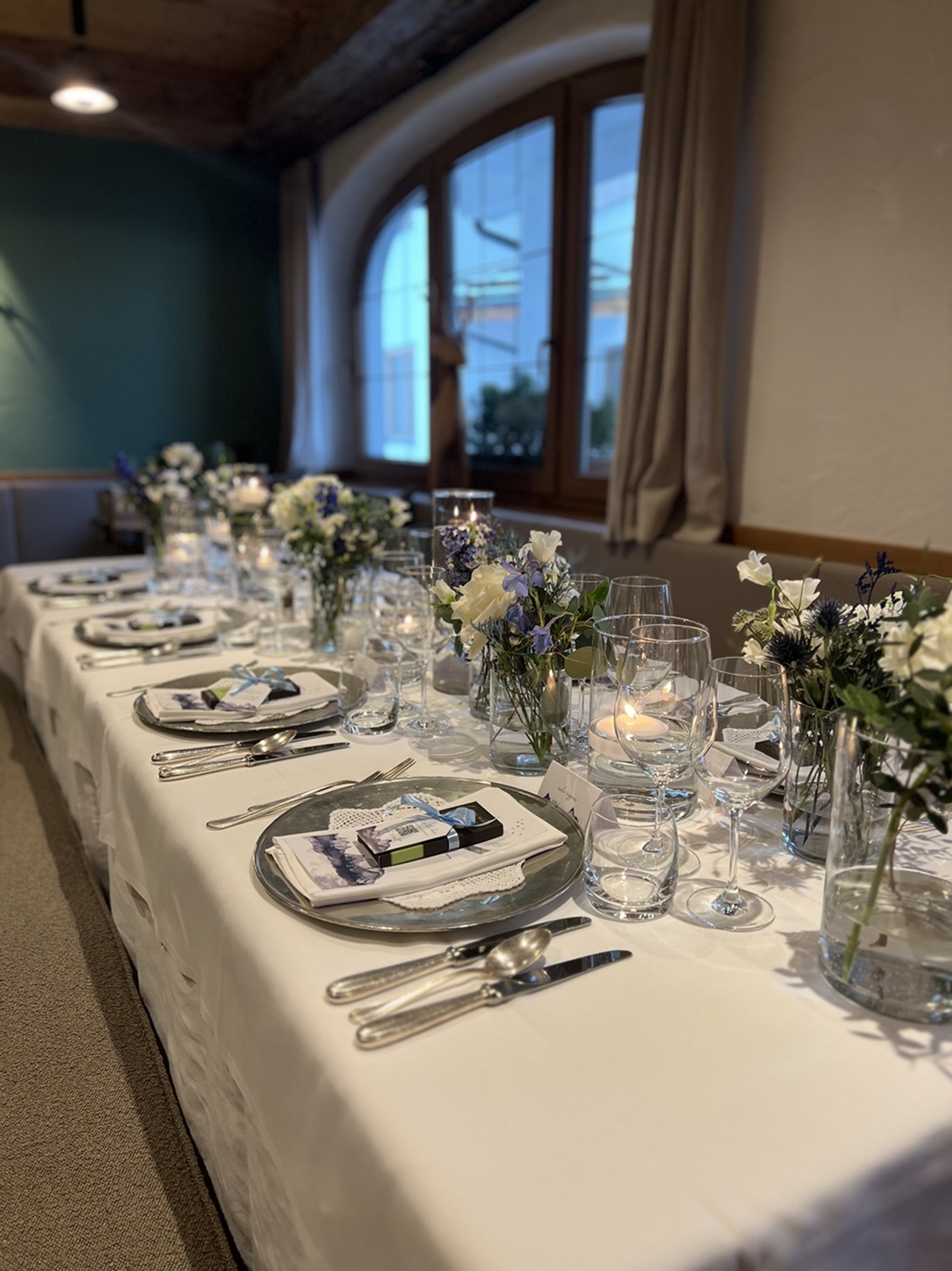 Elegant set table for a formal winter wedding dinner, decorated with flowers, candles, and neatly arranged plates and cutlery.