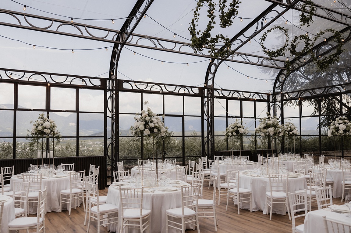 Festlich gedeckte Tische in der Glaslocation von Schloss Freudenstein – stilvolle Hochzeitslocation in Südtirol mit Panoramablick auf die Berge, ideal für moderne Berghochzeiten.