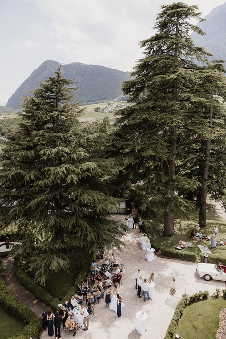 Sektempfang unter alten Bäumen mit Blick auf die Südtiroler Berge – stilvolle Berghochzeit auf Schloss Freudenstein, organisiert von einer erfahrenen Hochzeitsplanerin.